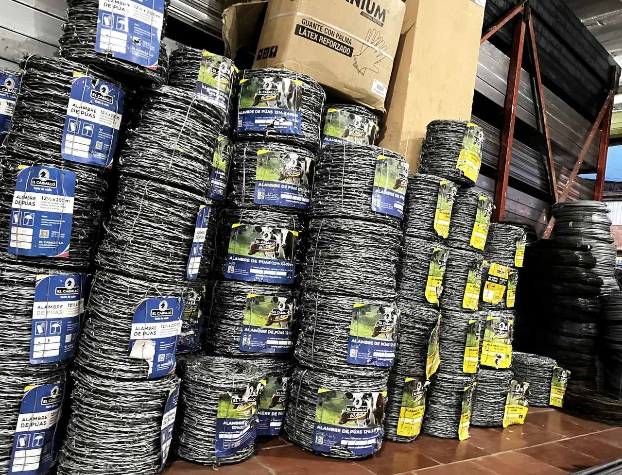 Rollos de alambre de púas El Caballo apilados en la bodega de Ferretería El Industrial