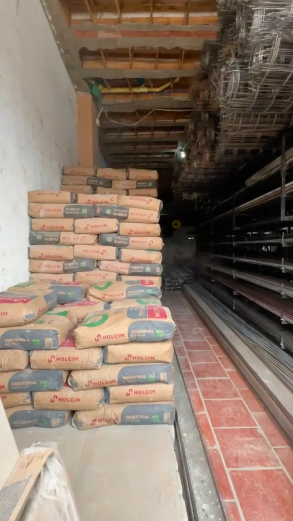 Estibas de cemento Holcim junto a malla electrosoldada y perfilería dentro de la bodega