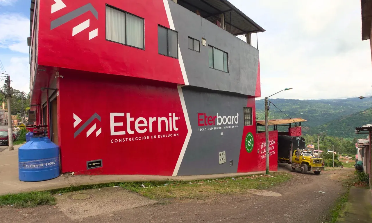 Costado del almacén con acceso vehicular y un camión cargando materiales de construcción