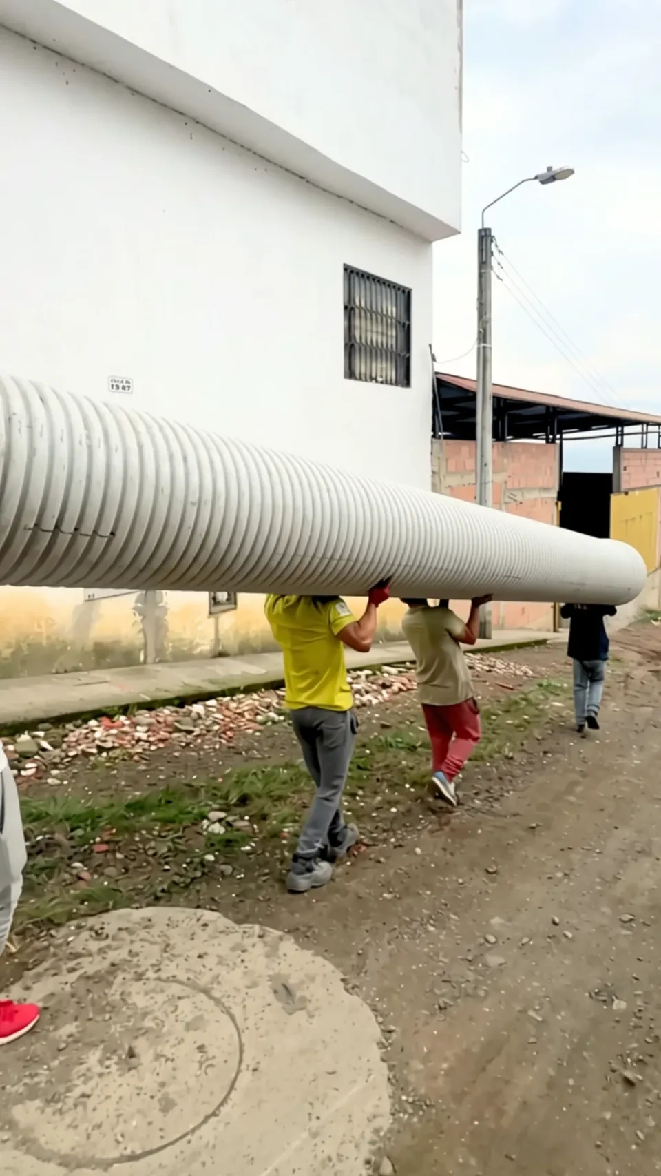 Personal del almacén cargando un tubo corrugado de gran diámetro para entregarlo a una obra